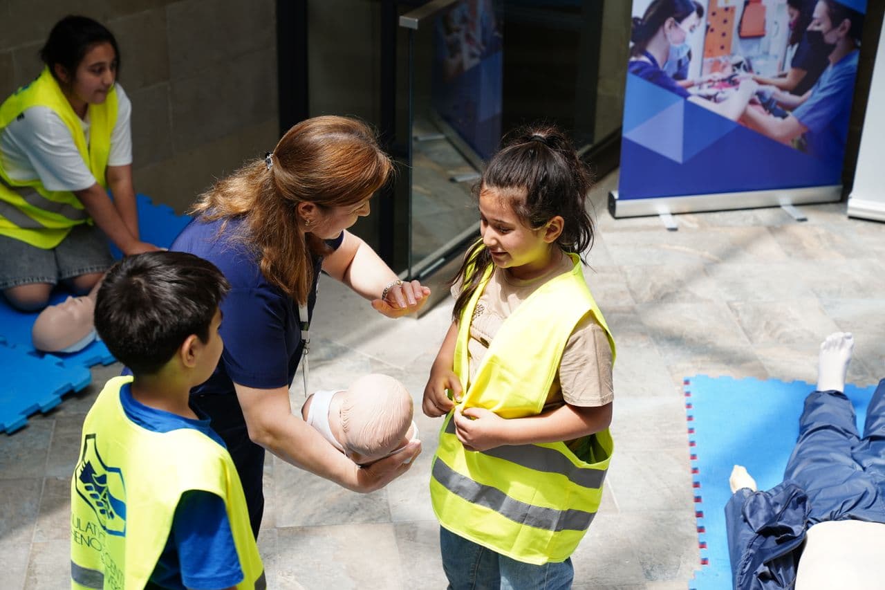 A first aid instructor teaching children paediatric first aid with an infant manikin